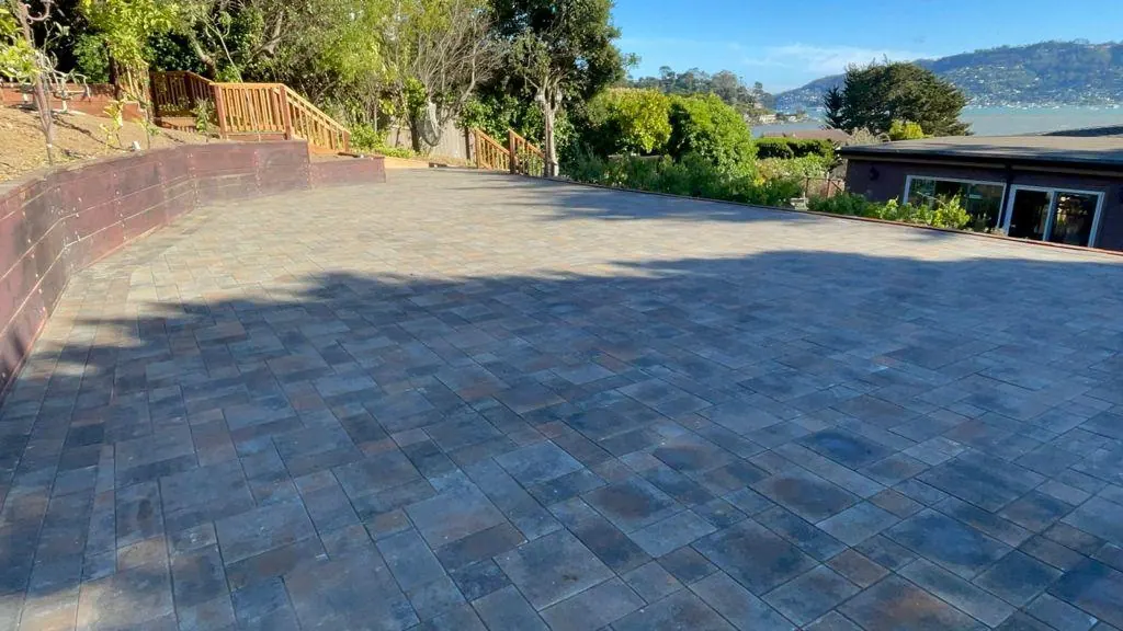 Large paver patio with a curved retaining wall and a bay view