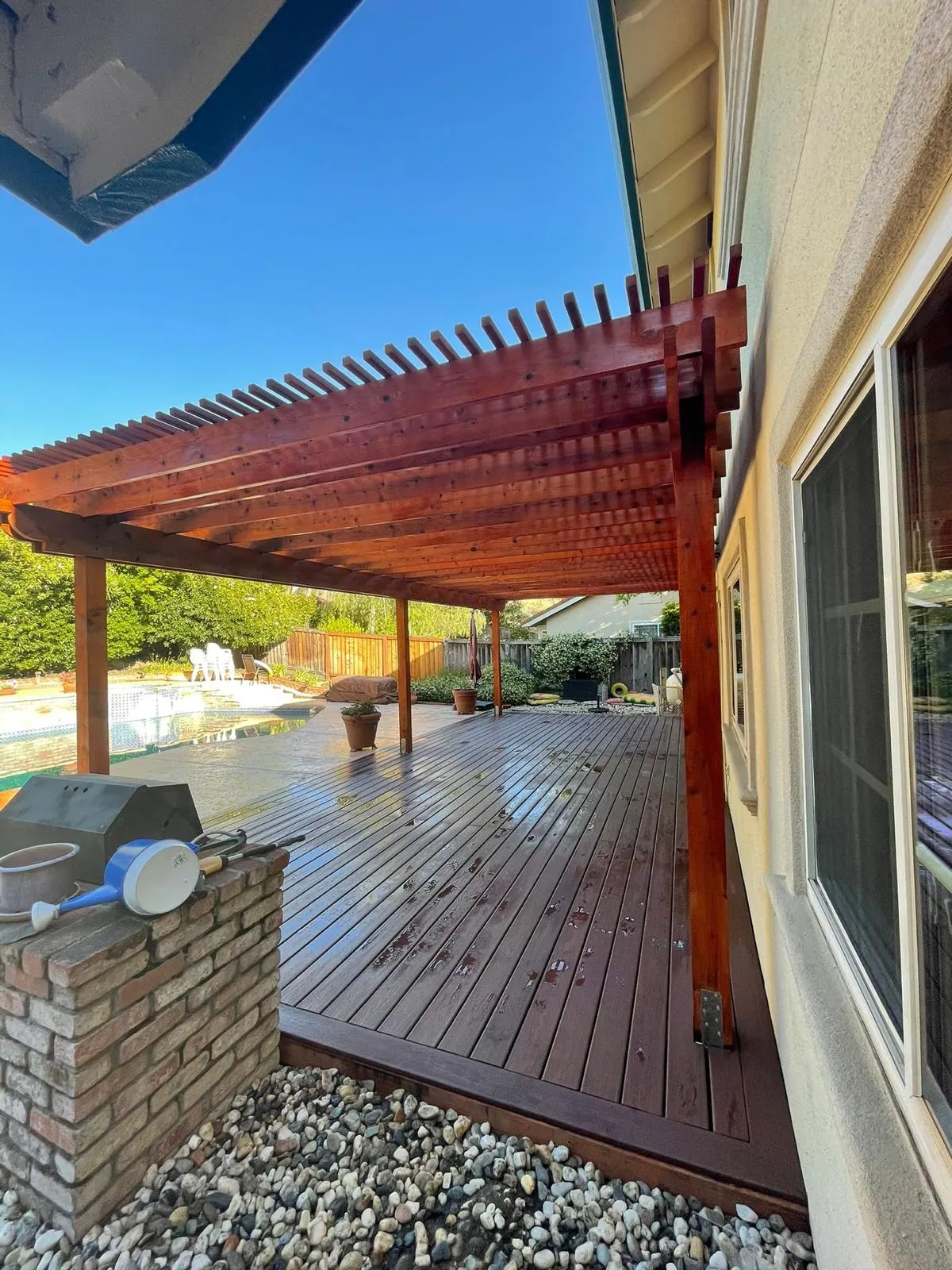 Redwood deck with an attached pergola and brick BBQ